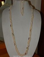 Twisted seed pearl necklace displayed on white bust form with matching seed pearl bracelet on an arm stand