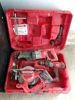 Red plastic Milwaukee branded carrying case with three power tools inside: reciprocating SawzAll, hammer drill, and circular saw all fitting in molded compartments.