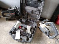 Three power tools including Craftsman planer, Porter Cable pneumatic nailer in case, and Craftsman sander on concrete floor.