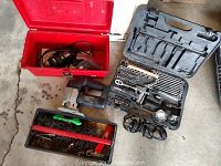 Photo showing Craftsman sabre saw, incomplete socket set in black case, and red toolbox with broken handle and assorted loose hardware.