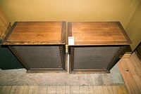 Top view of two wooden cabinet speakers placed side by side, showing wear on wood surfaces.