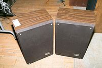 Pair of Zenith Allegro MC300 speakers with wood grain finish and black fabric speaker covers attached in front, showing condition of wood and fabric.