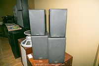 Four speakers stacked in pairs on a wooden surface, two smaller Koss speakers on top of two larger Acoustic Profiles speakers, showing overall condition and size comparison.