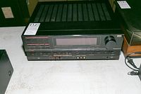 Sansui audio video stereo receiver S-X1130 showing the full front panel with various control buttons and tuning dial, placed on a low table surface.