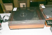 Full front view of the Lenco B55 turntable with closed dust cover showing wooden base and power cord.