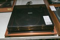 Front view of vintage Connoisseur turntable with closed dust cover and wooden base visible.
