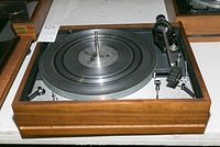 Full view of Dual 1219 turntable showing wooden plinth and metal platter without cover or needle.