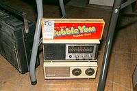 Three radios stacked. Top radio has Bubble Yum Bubble Gum branding. Middle radio is Panasonic model 6283C. Bottom radio is a cream-colored Zenith B210L with two large knobs.