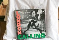 The Clash London Calling vinyl record album cover, showing black and white photo of man smashing guitar, with red and green text.