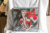 Photo showing vinyl record album with Billy Idol cover artwork, mainly red and beige colors, featuring Billy Idol portrait.