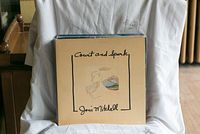 Photo showing Joni Mitchell 'Court and Spark' vinyl record LP with cream cover featuring minimalistic artwork and title.