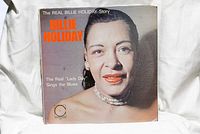 Front cover of The Real Billie Holiday Story vinyl record featuring a close-up portrait of Billie Holiday wearing pearl earrings and necklace.