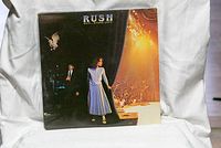 Front cover of Exit...Stage Left album showing a theatrical concert scene with band members.