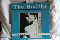 Front cover of The Smiths 'Hatful of Hollow' vinyl record with blue background and black and white photo of a man looking sideways
