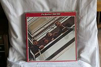 Front cover of The Beatles 1962-1966 compilation vinyl album showing band members looking down over a balcony, with a red border.