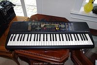 Front view of Yamaha electronic keyboard showing 61 keys, control panel and built-in speakers.