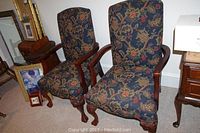 Pair of vintage-style upholstered chairs with floral patterned fabric, carved wooden legs, and claw feet.