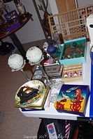 View of whole lot including candlesticks, decorative boxes, antique metal feet with wheels, plates, and small items on table.