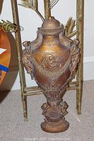 Close-up of ornate urn-shaped metal centerpiece with embossed figures.