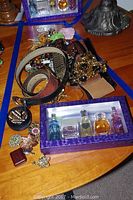 View of costume jewelry, leather belts, and set of mini perfume bottles on wooden surface