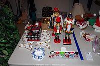 Full lot view showing nutcrackers, snowman figurines, plates, and ornaments on table