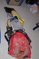 Overview photo showing nine assorted ladies purses and travel bags laying on the floor, displaying varying styles, materials, and colors.