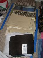 Folded upholstery fabrics laid on floor showing beige, tan, dark brown, and polka dot designs with various textures and a label.