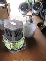 Overview photo showing both heaters: one propane heater with propane tank and another with coiled green hose.
