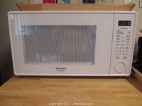 Front view showing white Sharp Carousel microwave oven with digital display and control panel.