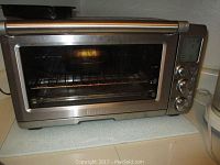 Front view of Breville toaster oven showing stainless steel finish, glass door, wire rack inside.