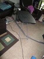 Side view of black adjustable folding tray table with foldable gray metal frame in living room environment.