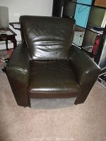Front view of chocolate brown leather recliner chair showing cushions, armrests, and leather texture.