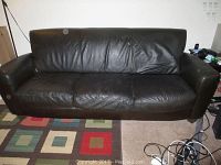 Front view of the chocolate brown Natuzzi leather sofa showing three seating sections and cushioned backrest.