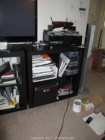 Front view of black IKEA 4-cube storage unit, showing general condition and compartments filled with various papers and items (not included) for display only.