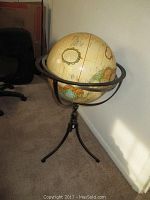 Full view of the Replogle globe mounted on a three-legged metal stand with meridian ring, showing the globe's size and condition.