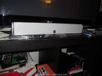 Wide view of Yamaha center speaker on shelf with plastic wrapping on the bottom frontage.