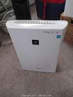 Front view of white Sharp air filter showing front panel and vent openings.