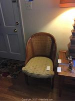 Full view of the walnut cane back chair with a curved design and yellow fitted cushion seat.