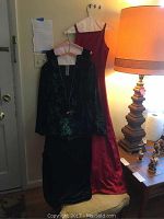 Full view of two gowns and green jacket hung on hangers, showing colors and lengths.