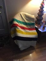 Full size Hudson Bay Point Blanket draped over a chair showing colored stripes on cream background in indoor lighting.