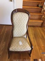 Front view of the wooden rocking chair showing upholstery and overall condition.