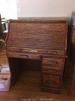 Front view of walnut roll top banker's desk showing slatted roll top and four drawers