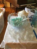 Showcase of punch bowl, tureen, ladle, and the 24 glasses on display on a table.