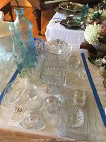 Top-down view of assortment of glassware on table including bottles, bowls, and candlestick holders.
