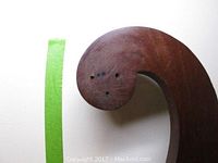 Close-up of the curved top part of the coat stand showing wood grain and hole marks