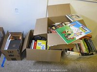 Two cardboard boxes containing various hardcover and softcover books.