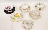 Top view showing all six teacup and saucer sets with different floral patterns and gold trim details