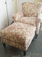 Front view of armchair with matching ottoman, showing beige floral patterned upholstery and dark wooden legs