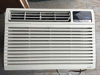 Front view of white Kenmore window air conditioner unit showing horizontal vents and control panel with PLASMAire branding and buttons.