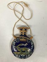 Front view of the hand painted ceramic pendant vessel showing the crocodile design and ornate detailing on a dark blue background with attached natural fiber cord.